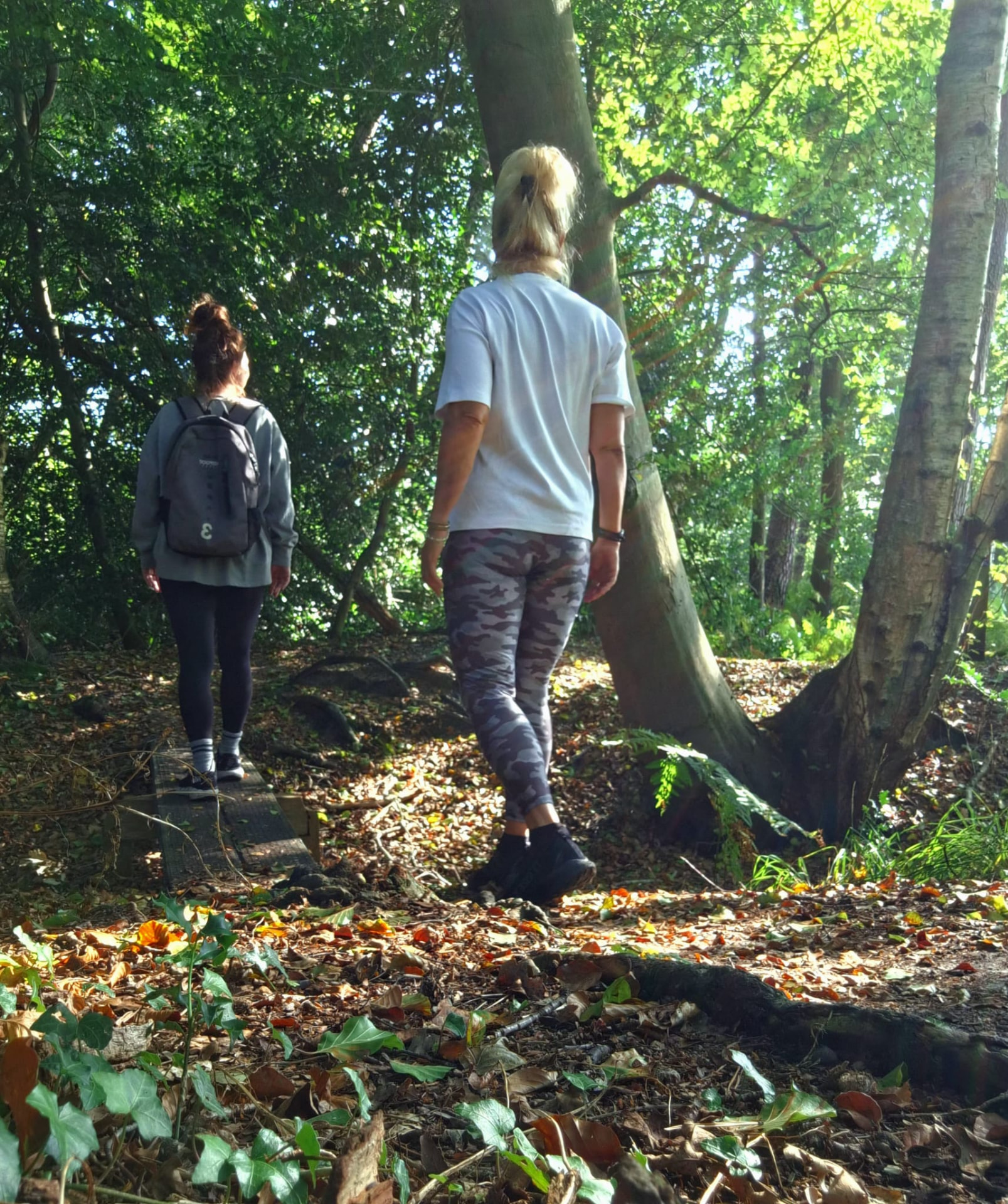 Twee vrouwen wandelen samen over een bospad tussen de bomen