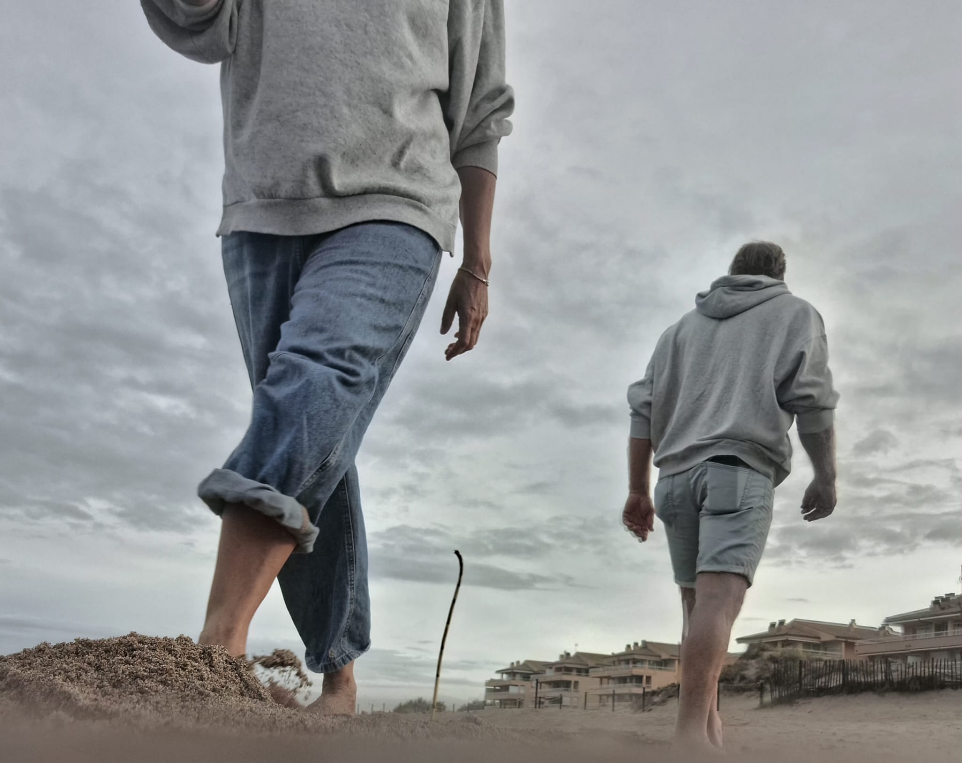 Twee mensen lopen blootsvoets over het strand, ieder in een eigen richting